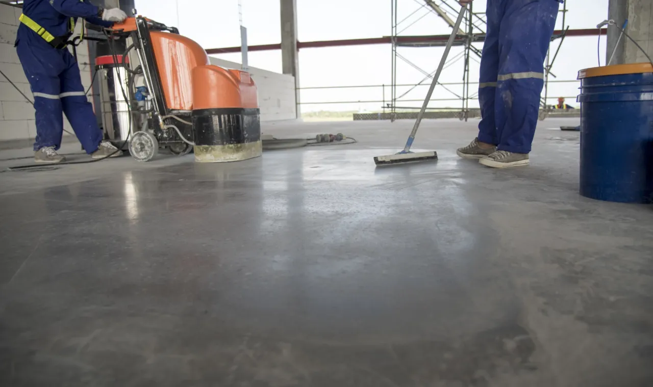 Reinigungskräfte reinigen den Boden auf einer Baustelle mit Scheuersaugmaschine und Wischmopp